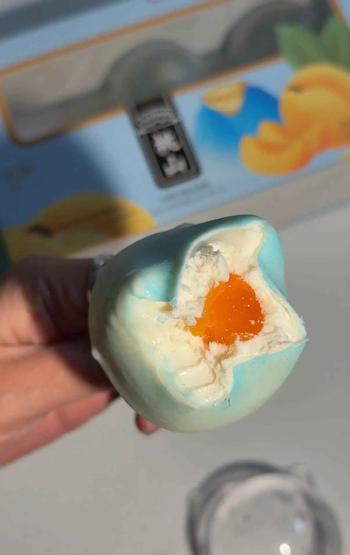 Blue mountain propitious fruit ice cream with creamy white and orange fruit filling held in hand