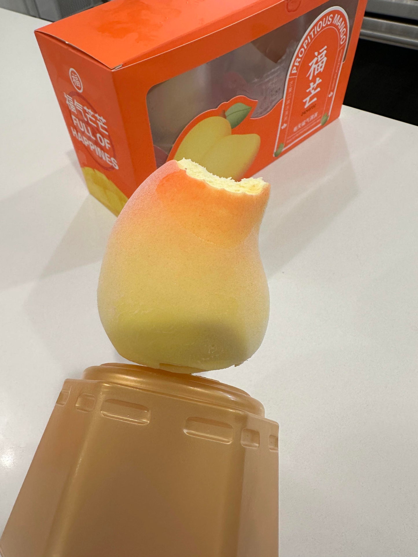RD International Market delicious mango peach fruit-flavored snack with a bite taken out displayed on beige surface