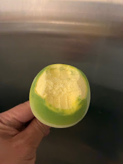 Hand holding a partially peeled green mango with yellow flesh inside